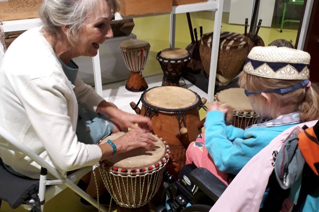 Girl in a wheelchair playing African drum with her grandmother