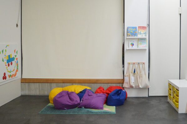 Photo of a room with white walls and colourful beanbag floor cushions.